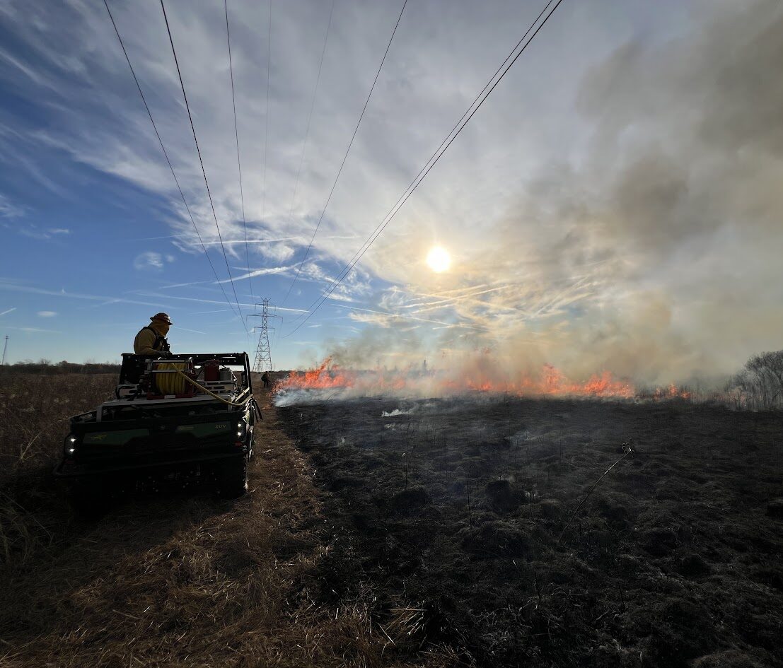 Fire personnel in Gator overlooking burning prairie