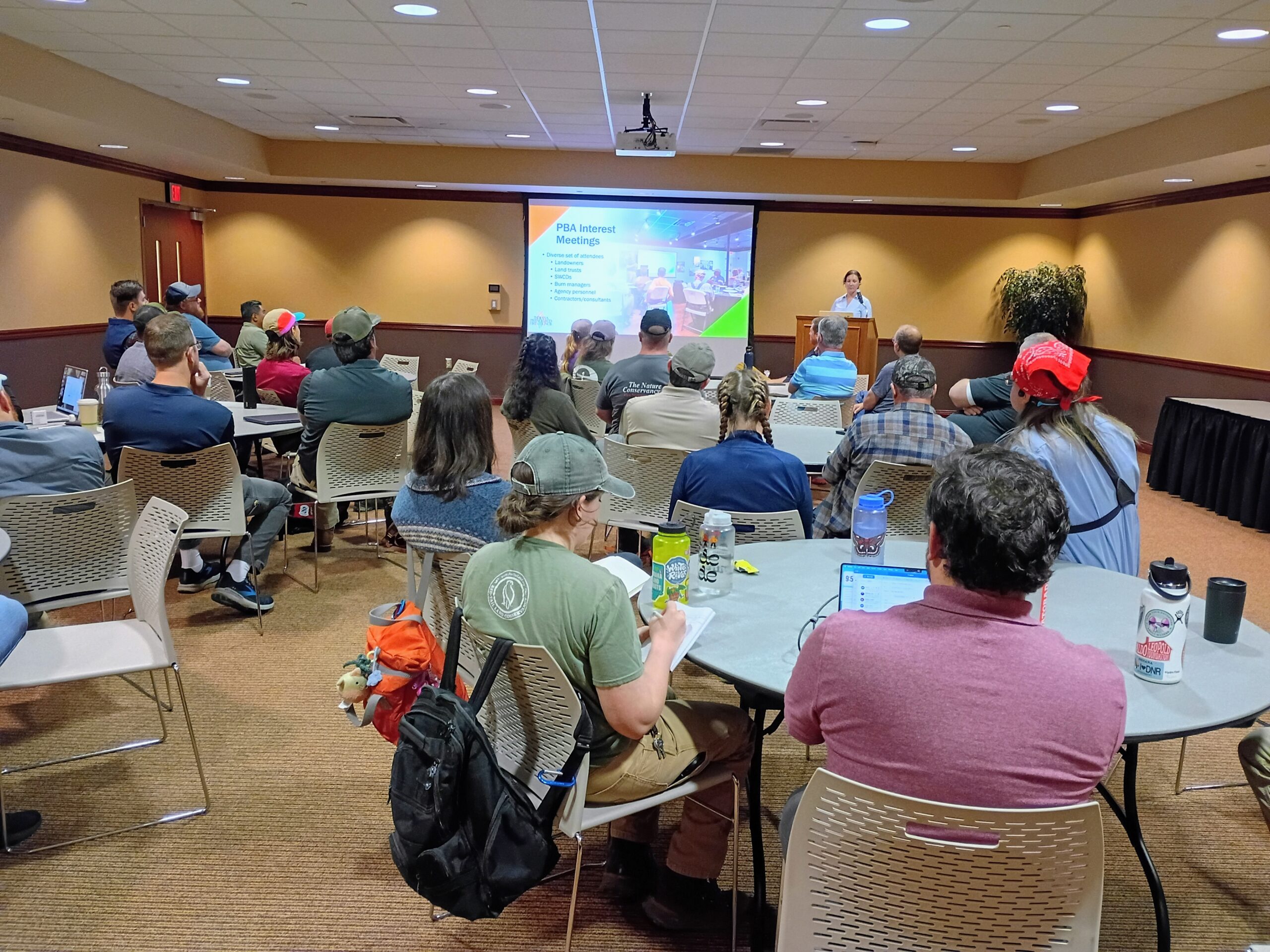 People around round tables watch a powerpoint presentation